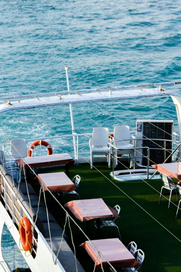 From above of contemporary deck with tables and chairs of yacht sailing in wavy blue sea