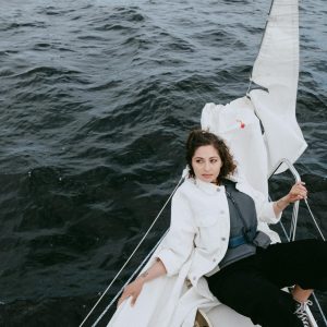 Woman in White Coat Sitting on White Boat